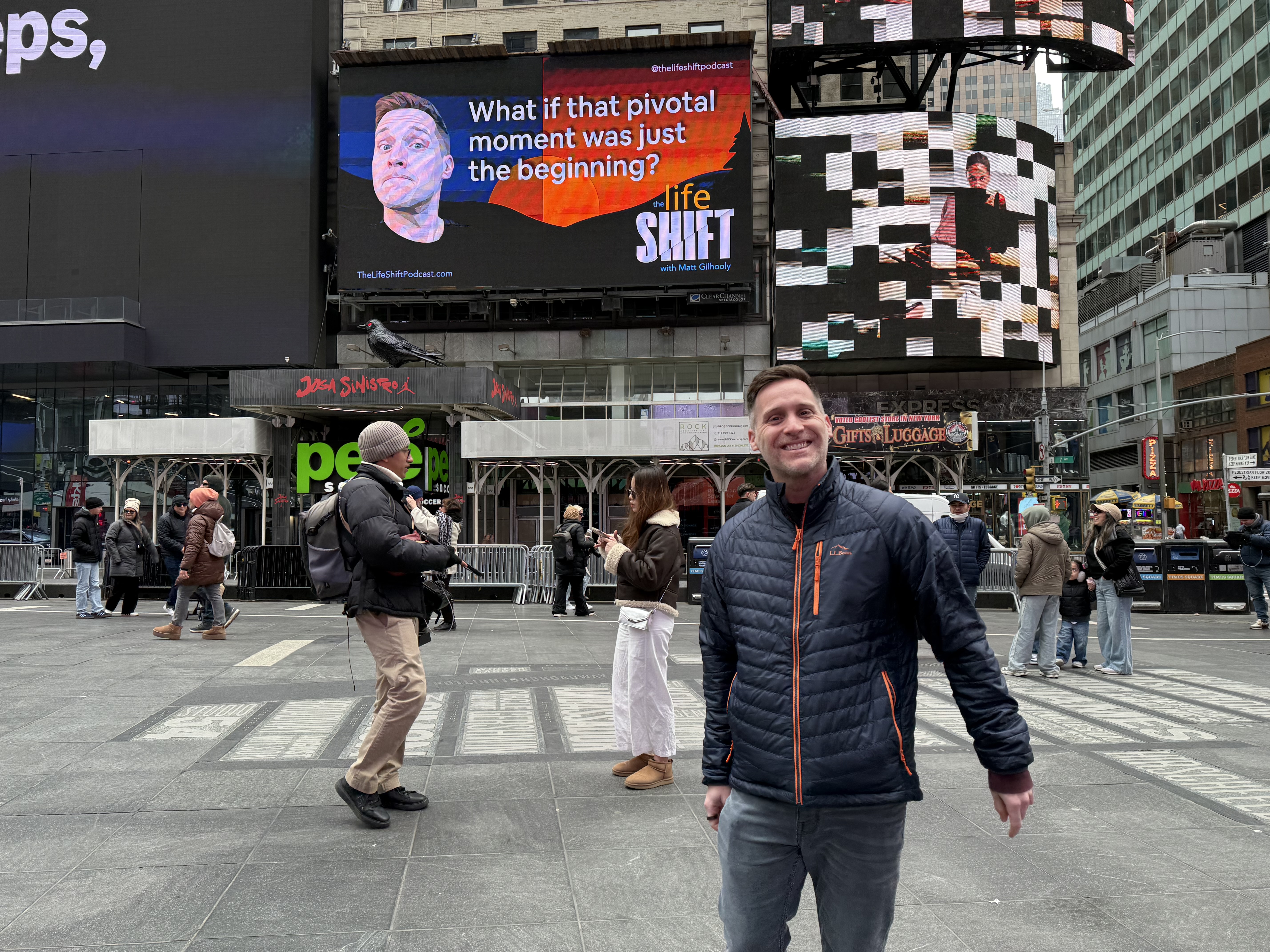 Matt Gilhooly standing in Times Square in front of a Life Shift Podcast billboard